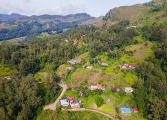A stunning aerial view of Maubisse village in the highlands of Ainaro, Timor-Leste. Houses are scattered across the ridges and valleys, surrounded by a vast, green mountain landscape