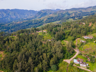 A stunning aerial view of Maubisse village in the highlands of Ainaro, Timor-Leste. Houses are scattered across the ridges and valleys, surrounded by a vast, green mountain landscape