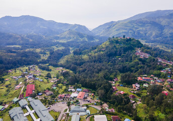 An aerial view of a public building complex, in the mountain town of Maubisse, Ainaro, Timor-Leste. The facility is set amidst a lush green highland landscape.