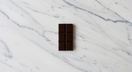 Minimalist top view of a single dark chocolate bar placed in the center of a white and grey veined marble background