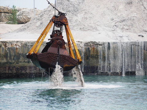 digger lifting sediment from the ground of a deep harbor dock