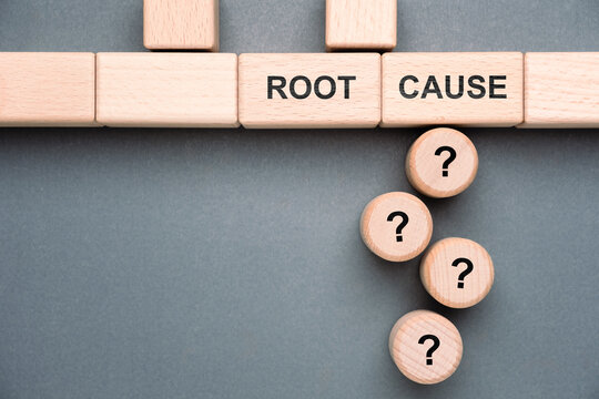 Wooden blocks arranged to show the phrase root cause with question mark symbols below representing problem solving, issue analysis, and finding the origin cause