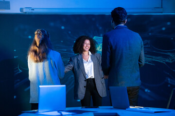 Diverse cybersecurity team celebrating a successful project with hugs and handshakes in a modern office.
