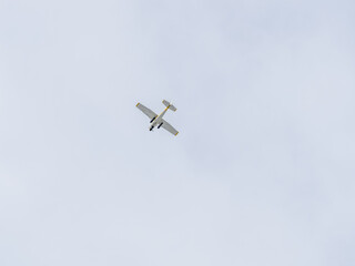 Small ultralight airplane with overhead wing and single propeller flying in sunset sky.