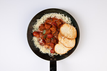 Meatballs with tomato sauce in a frying pan on a white background