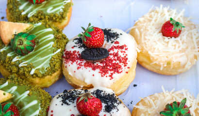 Close-up of a donut with strawberry topping. A collection of donuts arranged in a container.