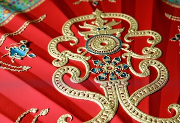 Obraz premium Intricate Gold Embroidery on Vibrant Red Fabric Featuring Ornamental Patterns and Complex Artistic Designs Embellished with Gems and Traditional Motifs