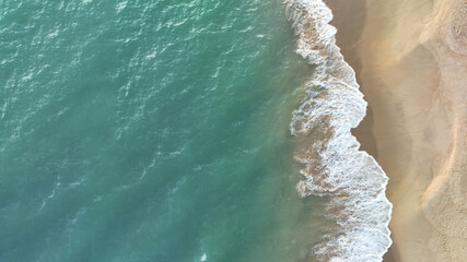 Beach top view of soft blue ocean wave on clean sandy beach and relaxing aerial scene, summer vacation holiday template banner. Waves surf with blue ocean lagoon