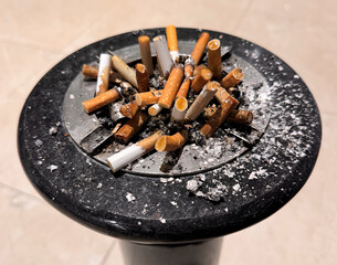 ashtray full of cigarette butts with ash everywhere