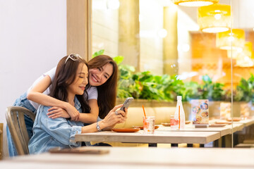 Happy beautiful Asian senior mother and adult daughter enjoy urban lifestyle using smartphone taking selfie together while shopping at department store. Family relationship and mother's day concept.
