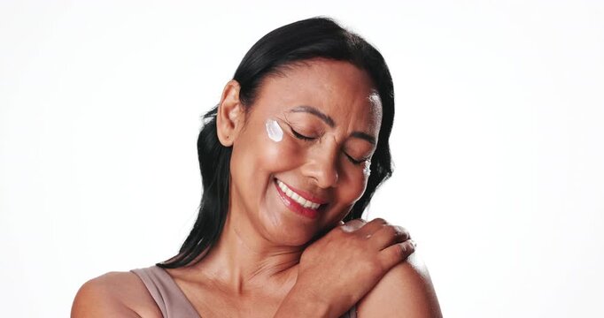 Smile, woman and lotion for skincare in studio for patch test, smooth skin and facial hydration. Happy, mature person and cream for moisture, collagen treatment and healthy shine on white background
