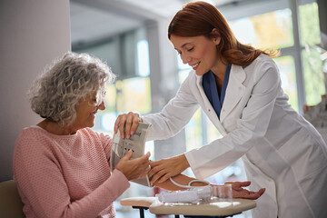 Plakat Senior woman getting her blood pressure measured by pharmacist in drugstore.