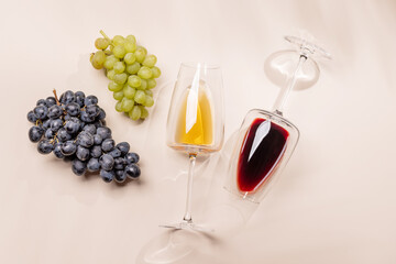 Wine glasses and grapes on beige background