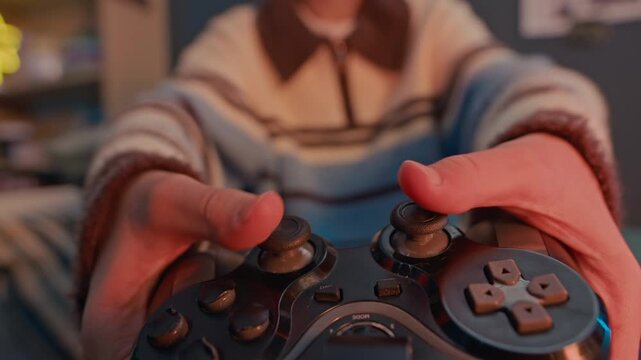 Tracking shot of young teen getting wireless joystick with buttons for video gaming and starting playing at home