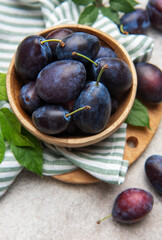 Fresh ripe plums filling a wooden bowl