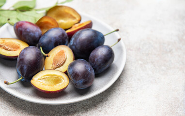 Fresh plums on plate showing halved fruit composition