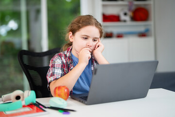 Kid studying at home school with laptop and books. Child doing homework during homeschool lesson. Young student learning in home school environment. Boy focused on study at home school desk.