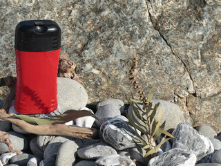 Plastic red beauty jar against backdrop of natural elements. Cosmetics and facial and hair care. Mock-up template for design. Eco-friendly products. Background, design composition.