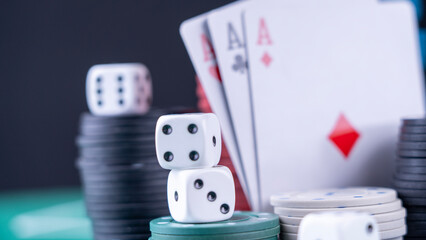 Fototapeta na wymiar A pile of poker chips and dice on a table. The dice are white and black, and the chips are green and white. Concept of excitement and anticipation, as if someone is about to play a game of poker