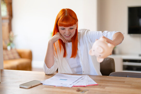 Young woman with red hair looks frustrated while checking finances at home