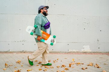 Man walking holding colorful skateboard on sidewalk.