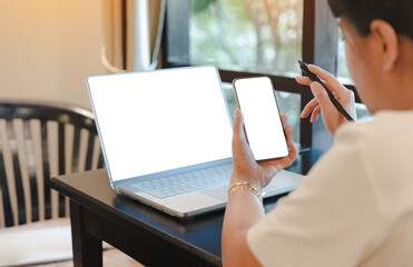 Businesswoman using smartphone,laptop with blank screens for mockup design,Concept for working...