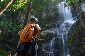 Adventurous hiker exploring jungle waterfall in sunlight