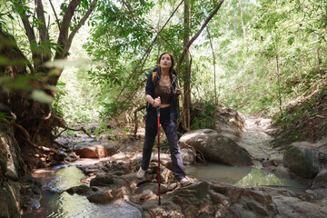 Young woman exploring stream during forest trekking expedition