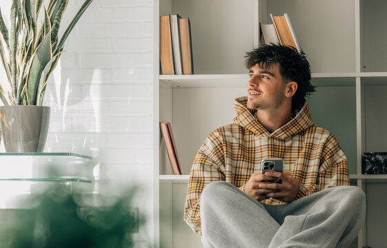 teenager at home with cell phone sitting on the floor