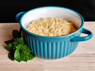 Creamy macaroni and cheese in blue ceramic bowl on wooden table.