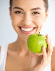 A radiant woman beams with pure joy, holding a crisp, green apple in her hand. The image captures the essence of health and vitality.