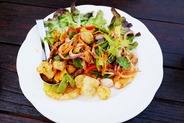 Fresh organic vegetable salad with crab sticks in white dish on wooden table. Healthy food