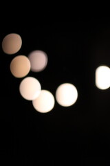 Abstract bokeh circles of blurred white and cream light on a black background, creating a soft, decorative effect.