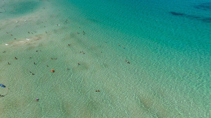 Aerial view of tourists swimming in the crystal-clear blue sea. Holiday concept.