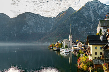 Fototapeta premium Scenic Lakeside Village with Church Tower and Mountain Reflection in Autumn