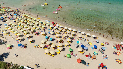 Aerial view of the beach at San Vito Lo Capo, located in the province of Trapani, Sicily, Italy. There are many beach resorts and parasols with tourists on holiday.
