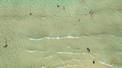 Perpendicular aerial view of the emerald green surface of the sea. There are people swimming. Ideal for backgrounds, textures and patterns.