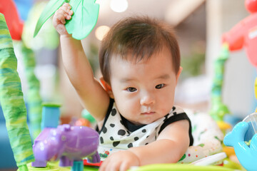 A baby is playing with a toy elephant. The baby is holding the elephant toy in its hand