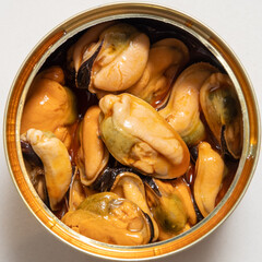 square picture, and upper view of an open can of pickled mussels on a white marble table