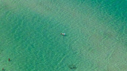 Aerial view of tourists swimming in the crystal-clear blue sea. Holiday concept.