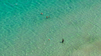 Aerial view of tourists swimming in the crystal-clear blue sea. Holiday concept.