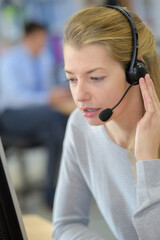 closeup of woman at computer wearing telephone headset