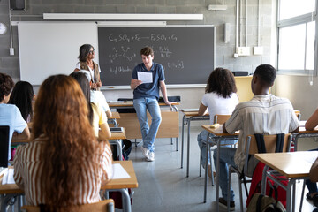 High school student reading to class during chemistry lesson