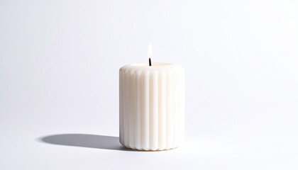 Lit, ivory-colored, ribbed pillar candle on clean white