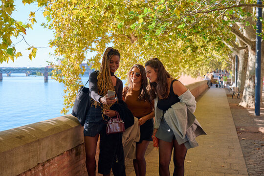 Young women friends sharing smartphone content in toulouse