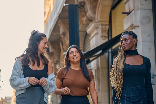 Diverse female friends walking and talking in toulouse city
