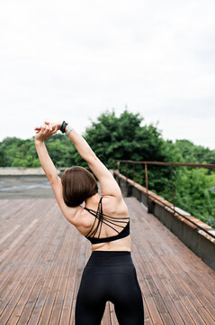 Back of sportswoman stretching on wooden terrace