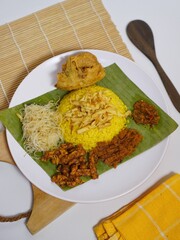 traditional indonesian yellow rice nasi kuning with side dishes for cultural food photography
