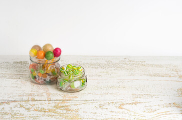 Multicolored and assorted lollipops are in glass jars on a gray background. View straight ahead