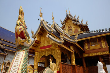 Fototapeta premium green Naga statue and ancient stucco art in front of golden ancient pagoda of buddhism at Wat Den Sali Si Mueang Kaen temple in Chiang Mai Province in Thailand